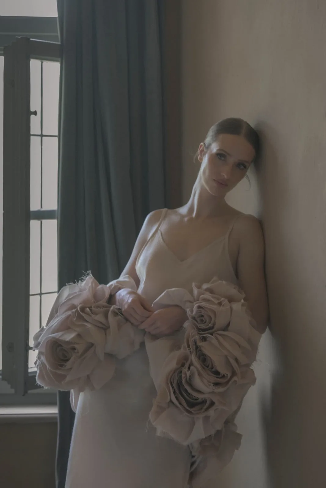 Bride leaning against the wall by the window at Schloss Haggenberg, waiting for the day to begin.