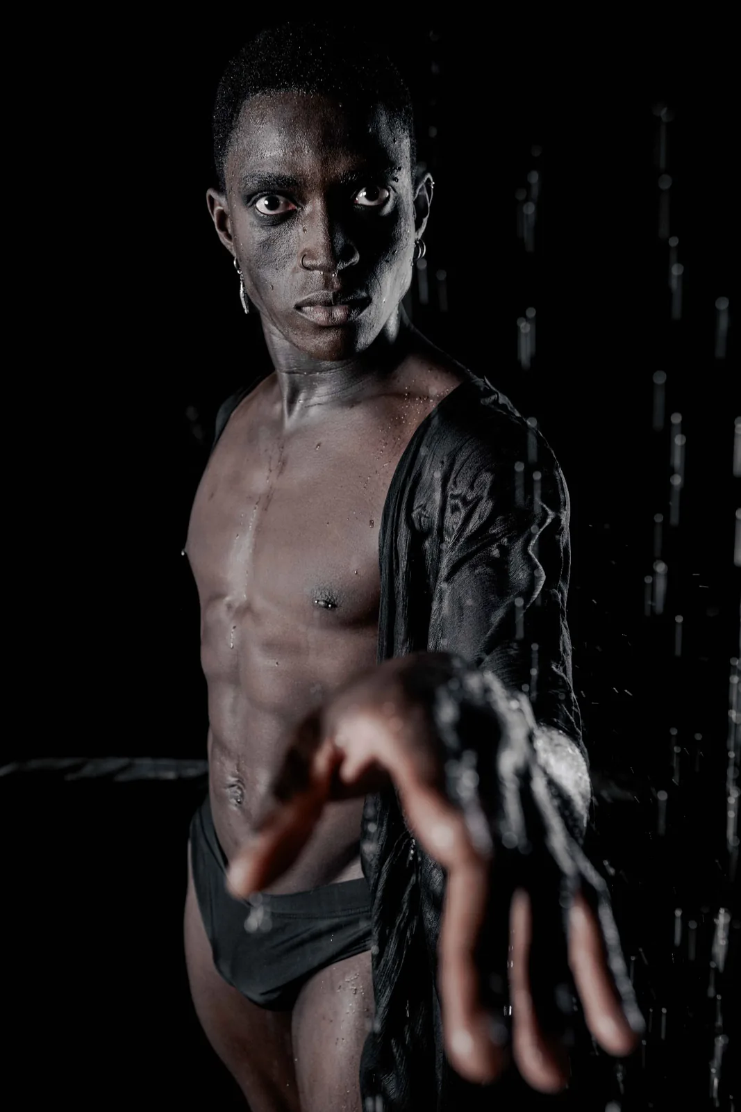 Dramatic low-key portrait of Kevin reaching towards the camera, water on his skin.
