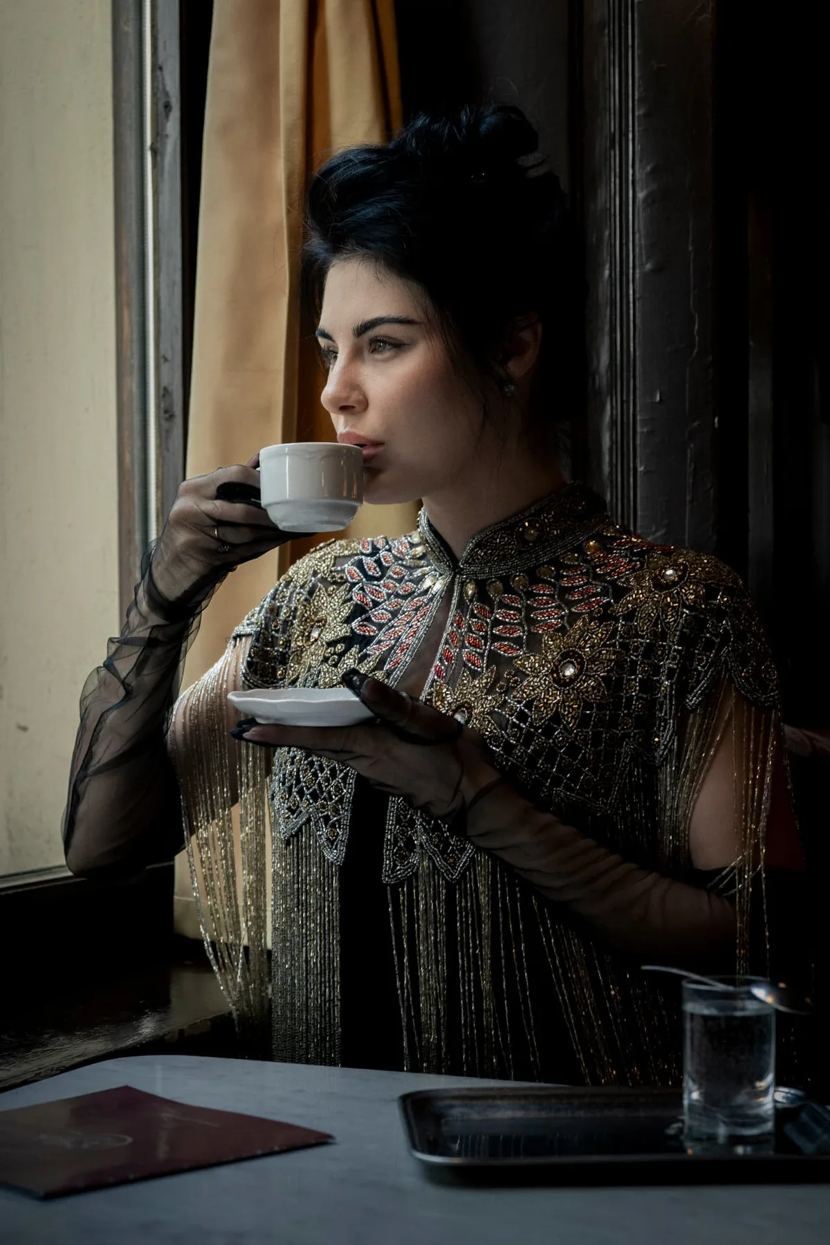 Izunia Motyl mit einer Kaffeetasse im natürlichen Fensterlicht des Café Sperl