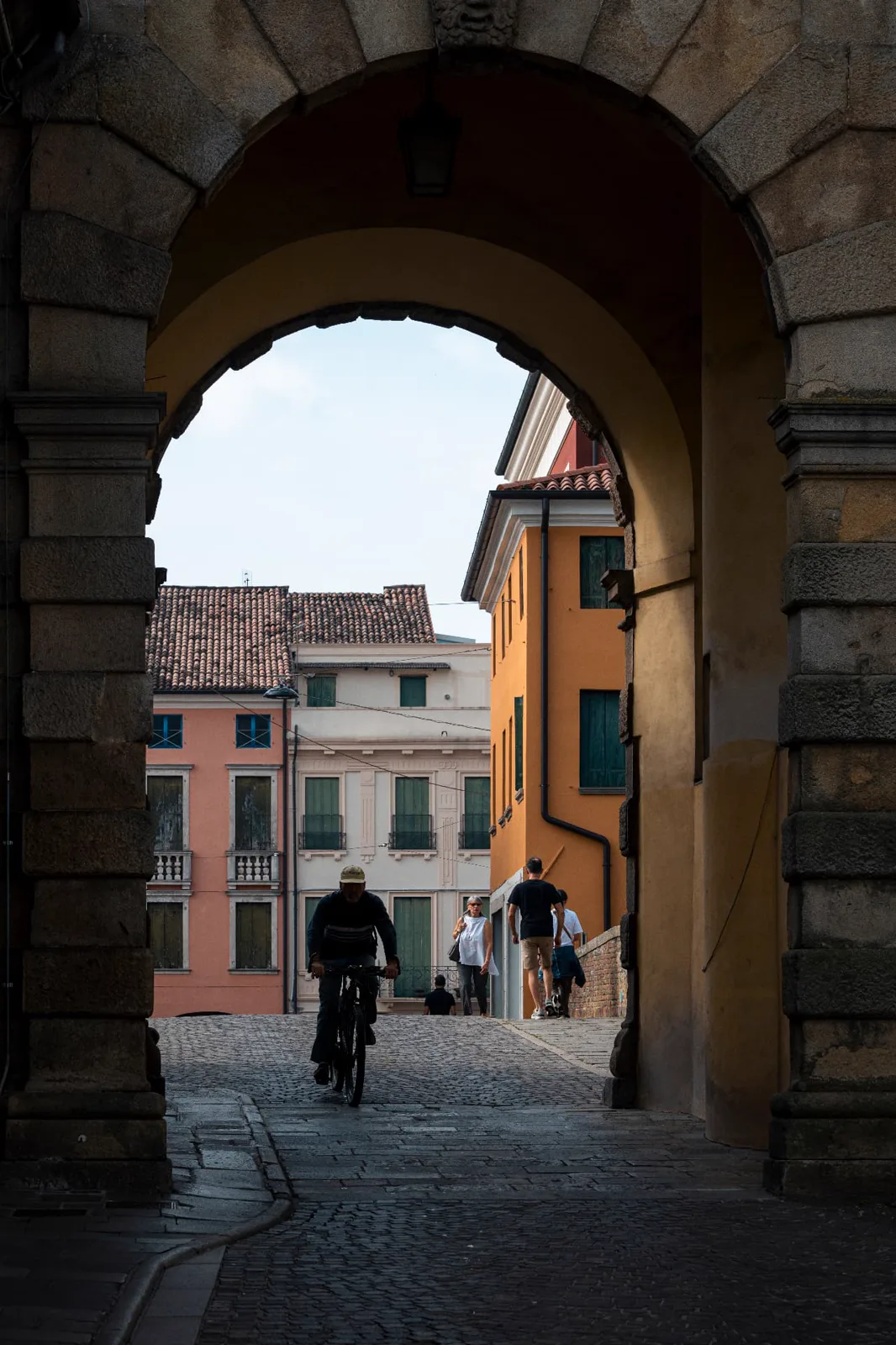 View through a historic town gate towards the colourful houses of Este