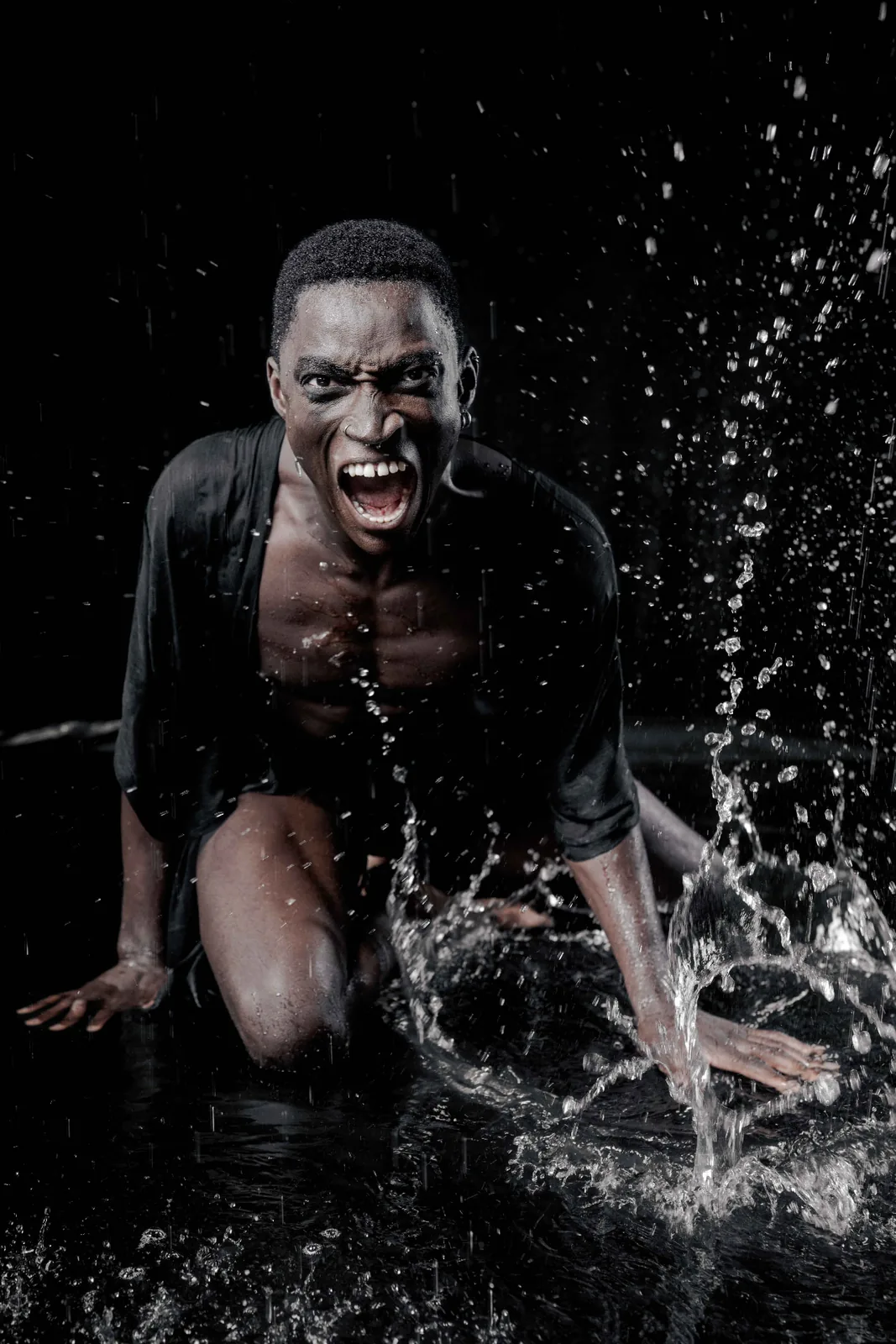 Kevin shouting in falling water, splashes frozen in hard editorial light.