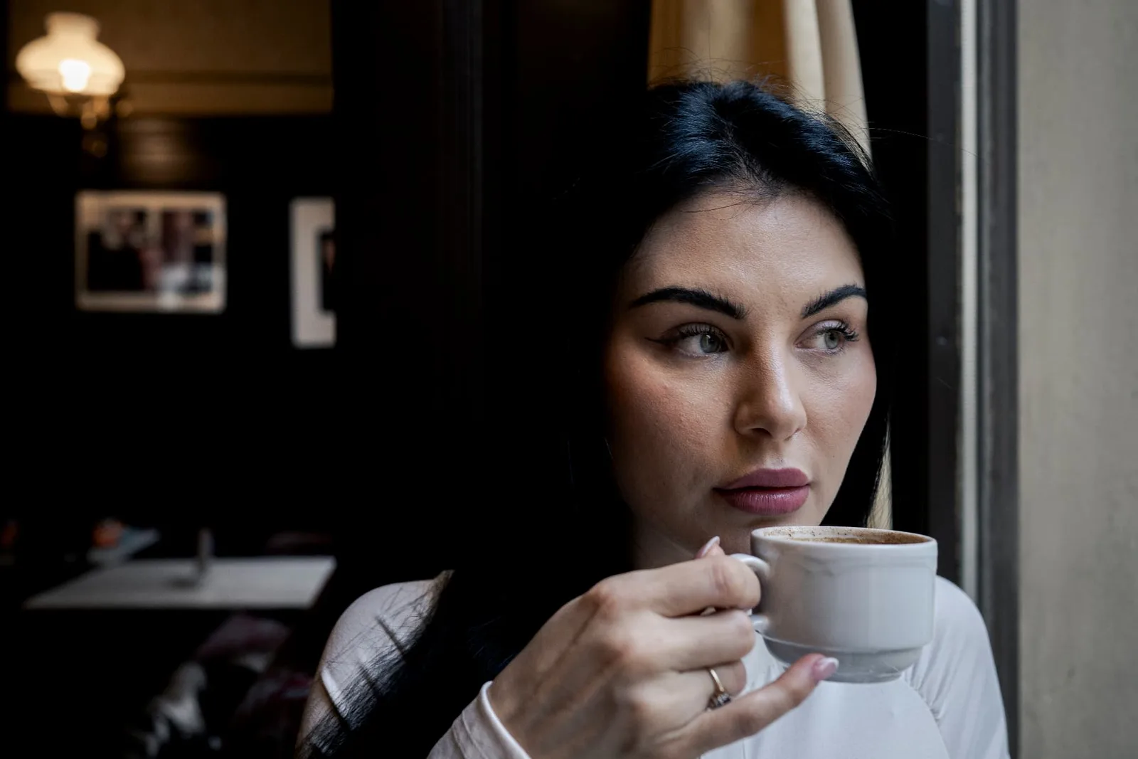 Intimes Editorial-Porträt von Izunia Motyl mit einer weißen Kaffeetasse im Café Sperl