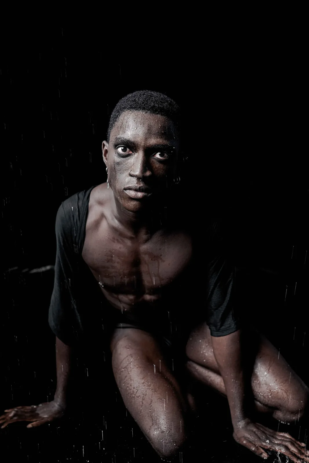 Kevin crouching in dark water, editorial fine-art portrait with hard side light.
