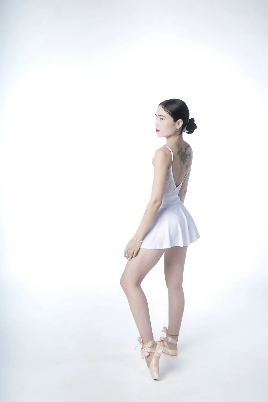 Ballet dancer Mia looking back over her shoulder, standing en pointe in a white studio in Vienna.