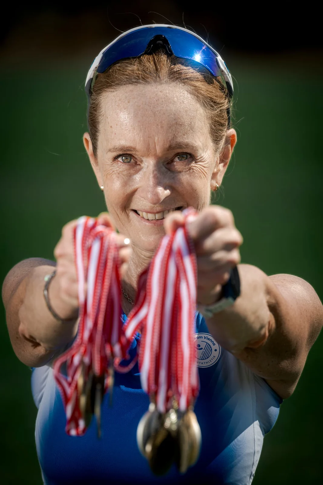 Birgit Pfeifer holds her running and championship medals towards the camera
