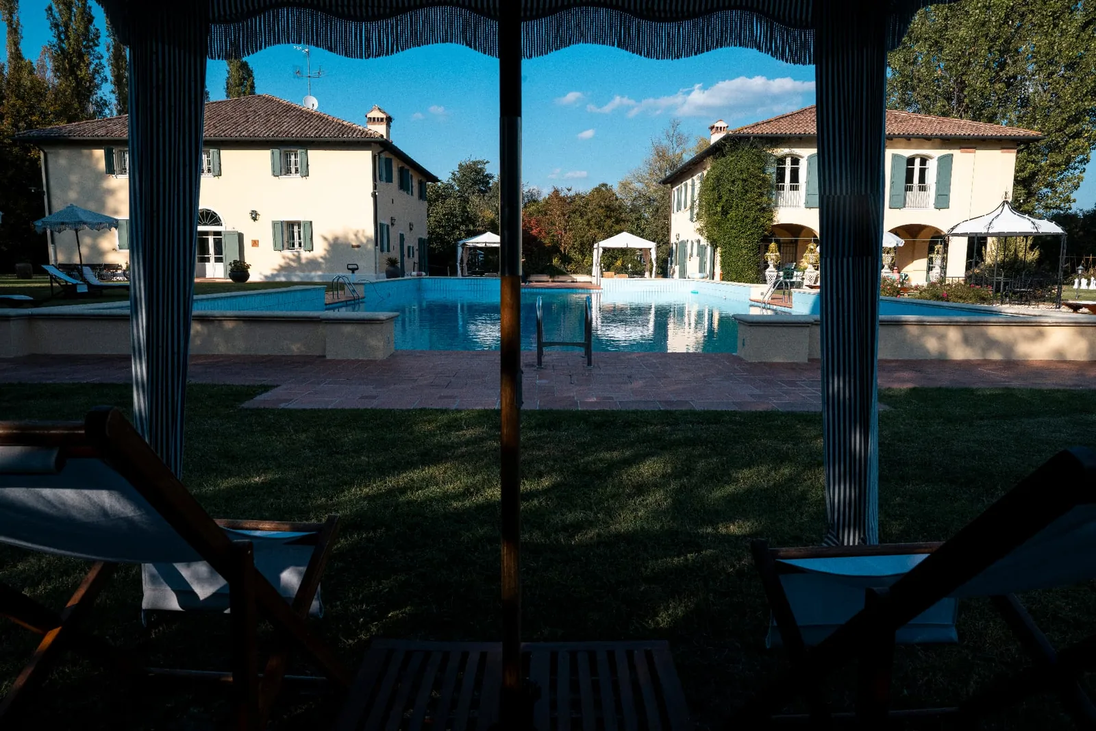 View from a shaded seating area towards the villa and pool