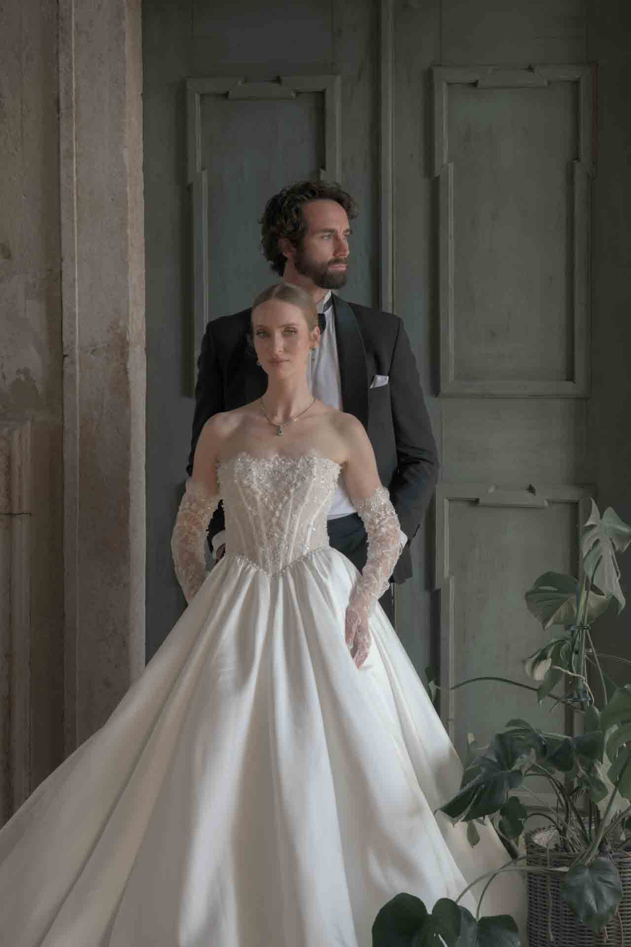 Braut im Couture-Kleid mit Bräutigam vor patinierten Türen im Wasserschloss Haggenberg — editorial fine art bridal portrait by Peter Scholz