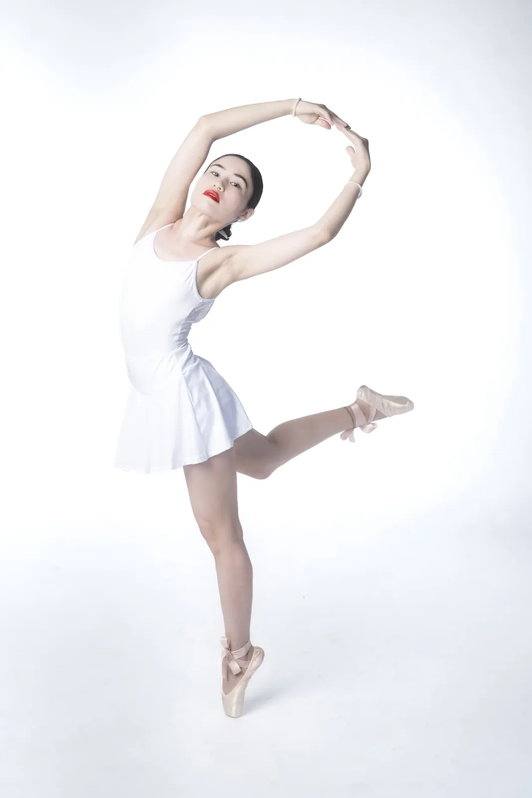 Ballet dancer Mia in attitude derrière en pointe in a white Vienna studio, her line held with complete control.