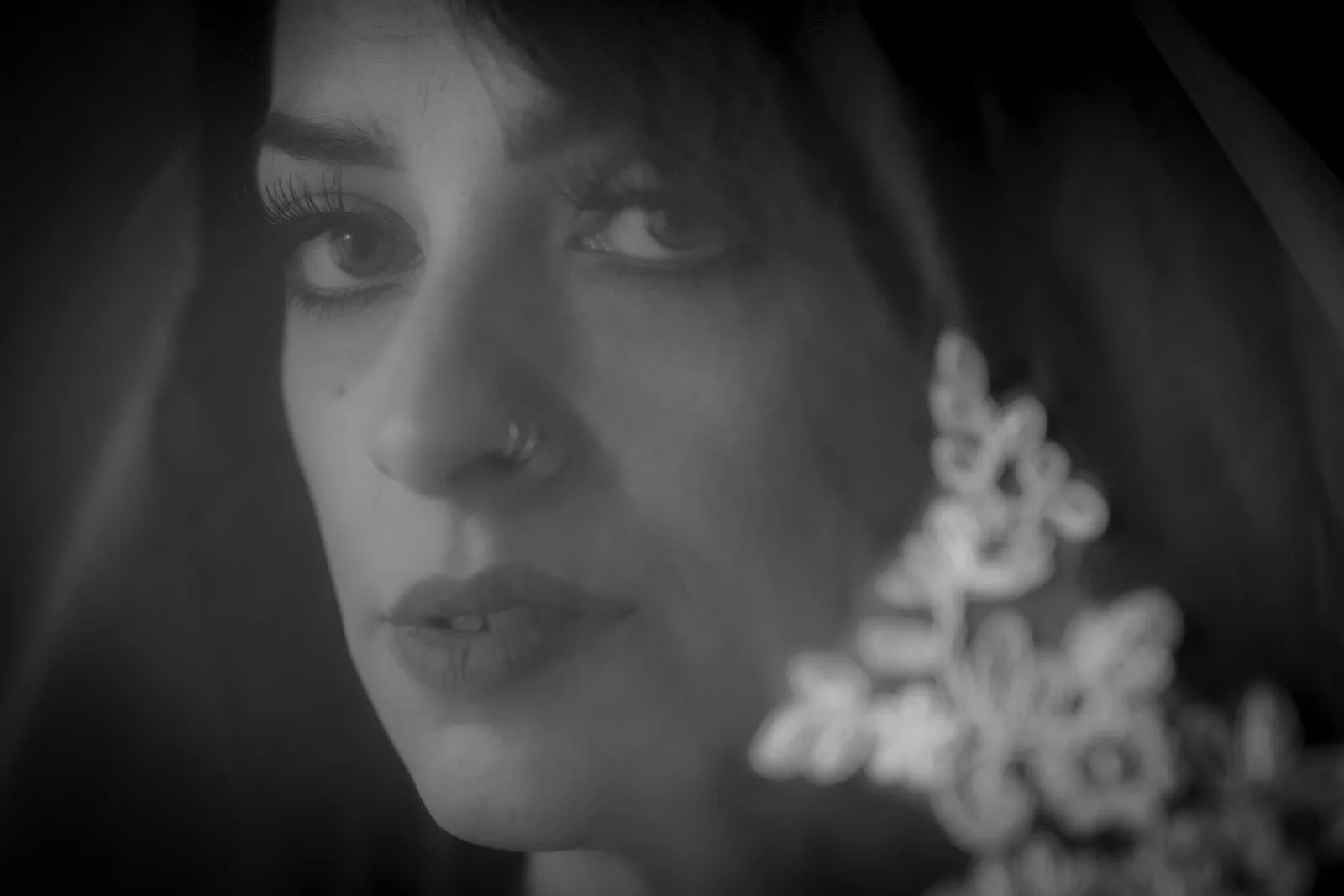 Black-and-white fine art close-up portrait of a woman behind delicate lace