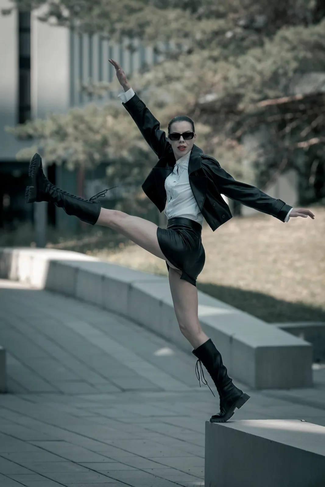 Available light editorial frame of Denisa Strakova balancing on a concrete bench in the open plaza around Messe Wien.