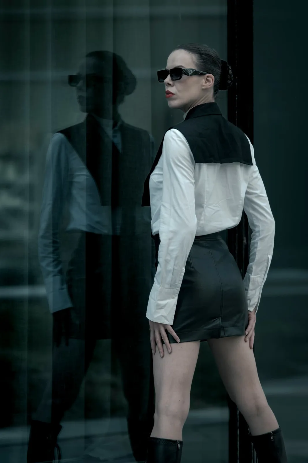 Editorial portrait of Denisa Strakova beside a glass facade in Vienna, her mirrored silhouette forming a second figure.