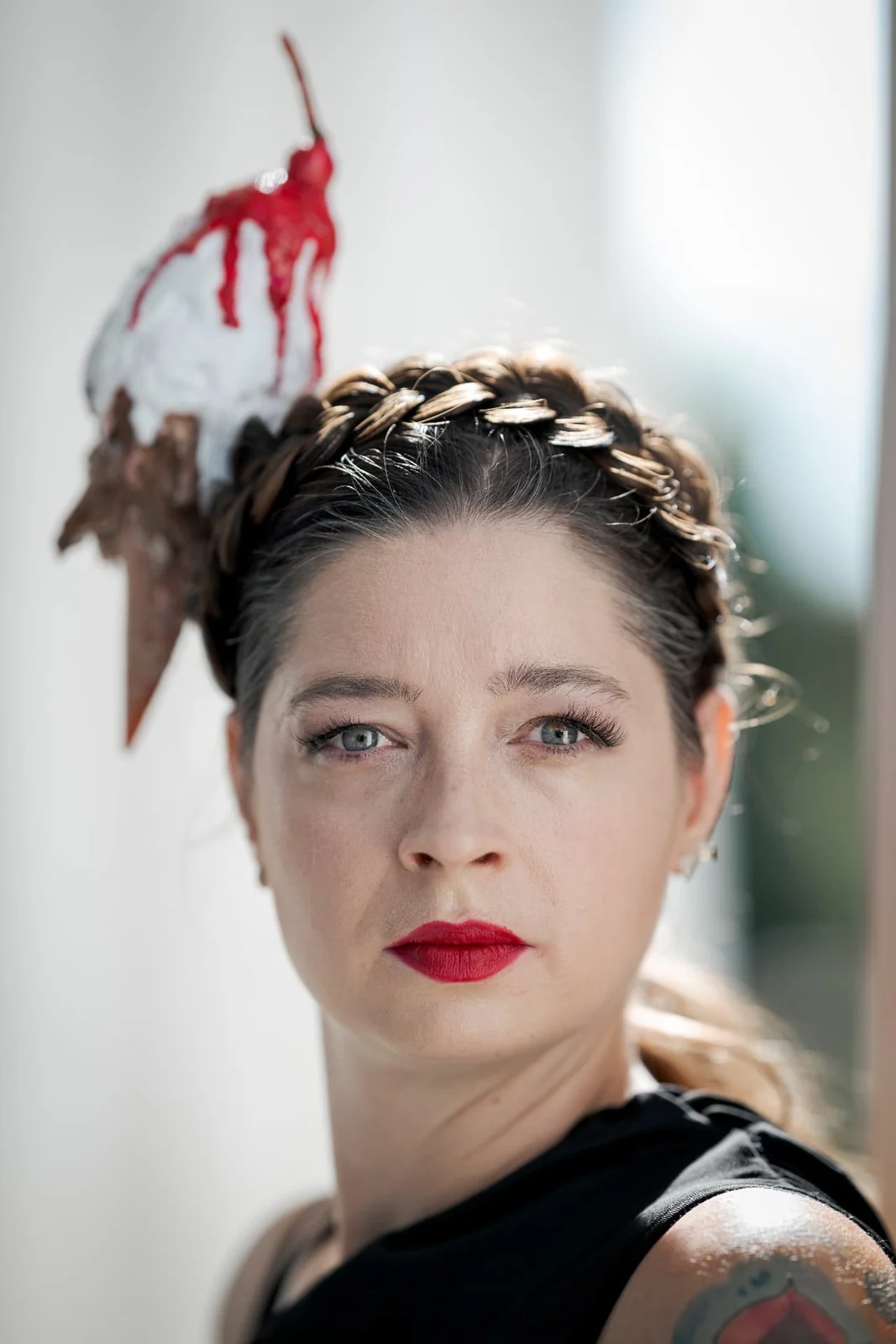 Fashion portrait of Asquina with a red sculptural creation above her head, pale columns of the Theseus Temple in Vienna behind her