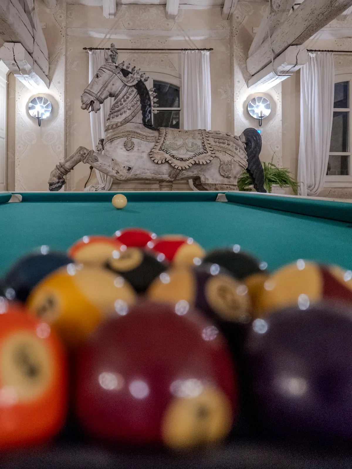 Billiard balls in the foreground with the horse sculpture in the background