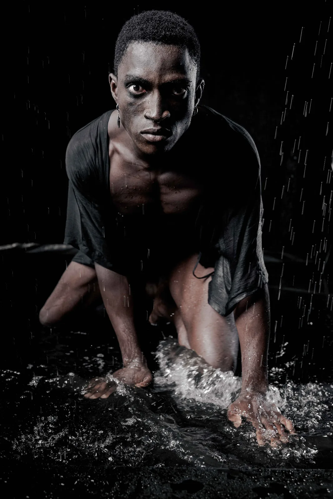 Kevin looking upward into falling water, dark low-key fine-art portrait.