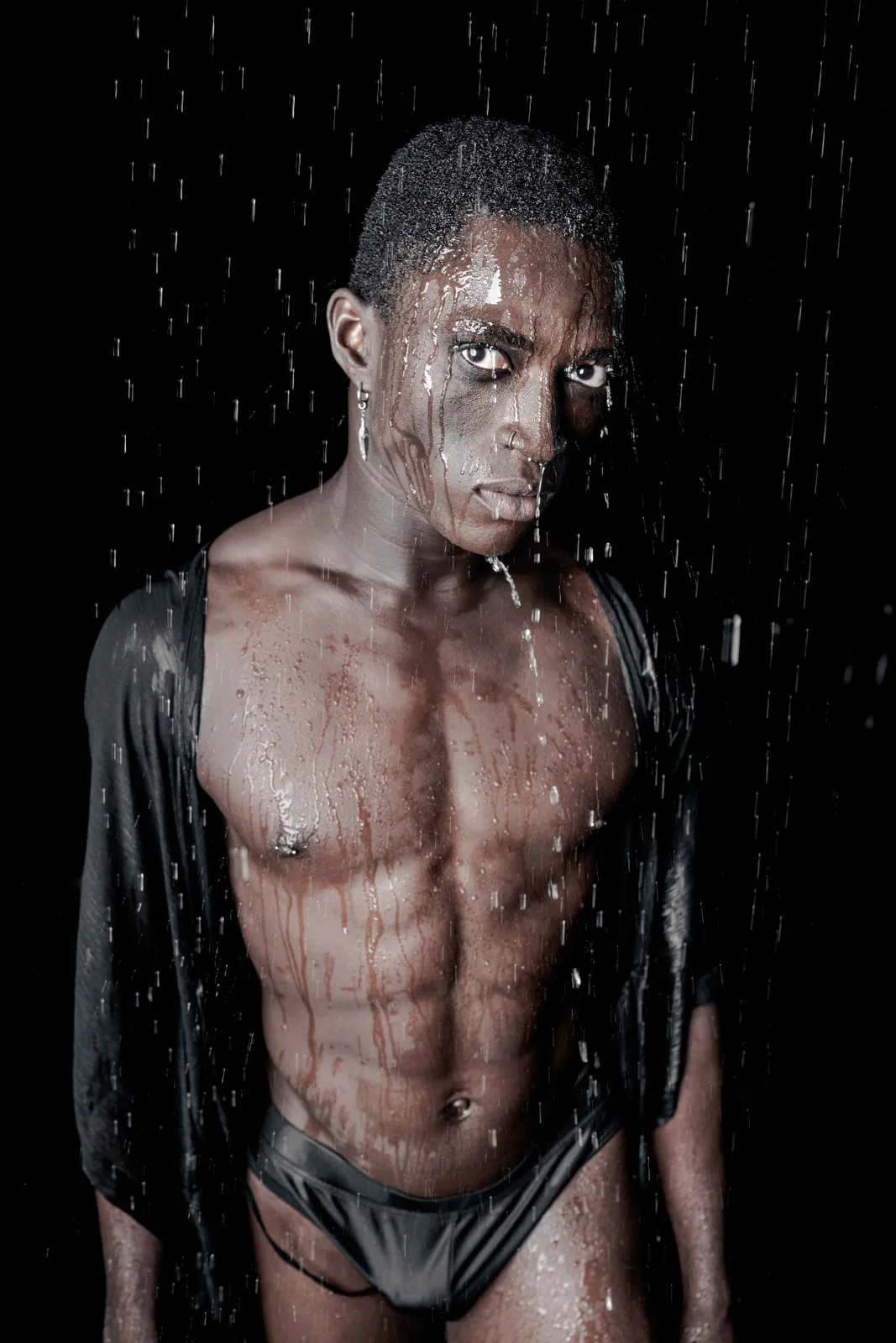 Rain portrait of Kevin against a dark background, water lines lit from the side.