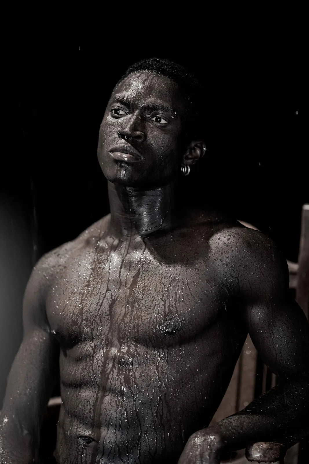 Kevin kneeling in water, looking calmly into the camera in dark editorial light.