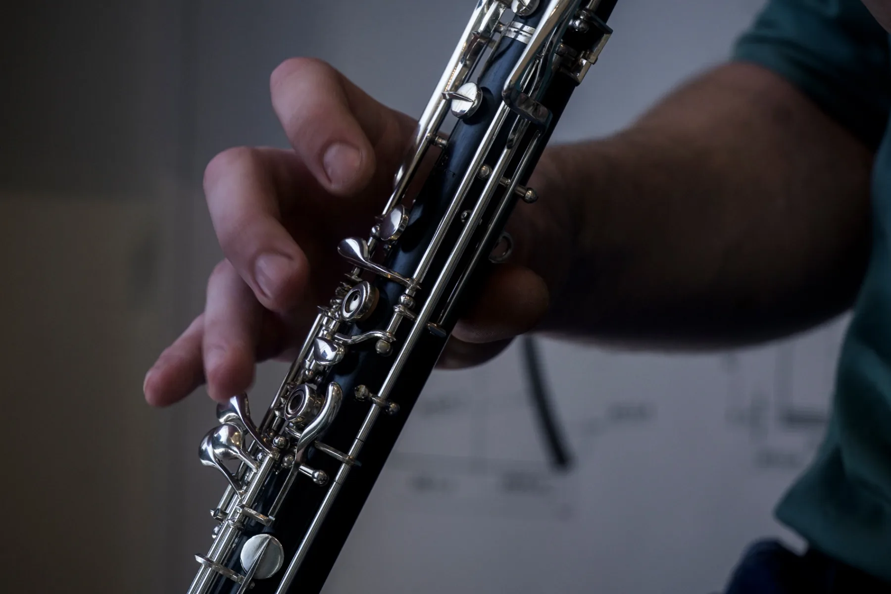 A musician's hand pressing the silver keys of a clarinet, the instrument responding to the lightest touch of the fingers.