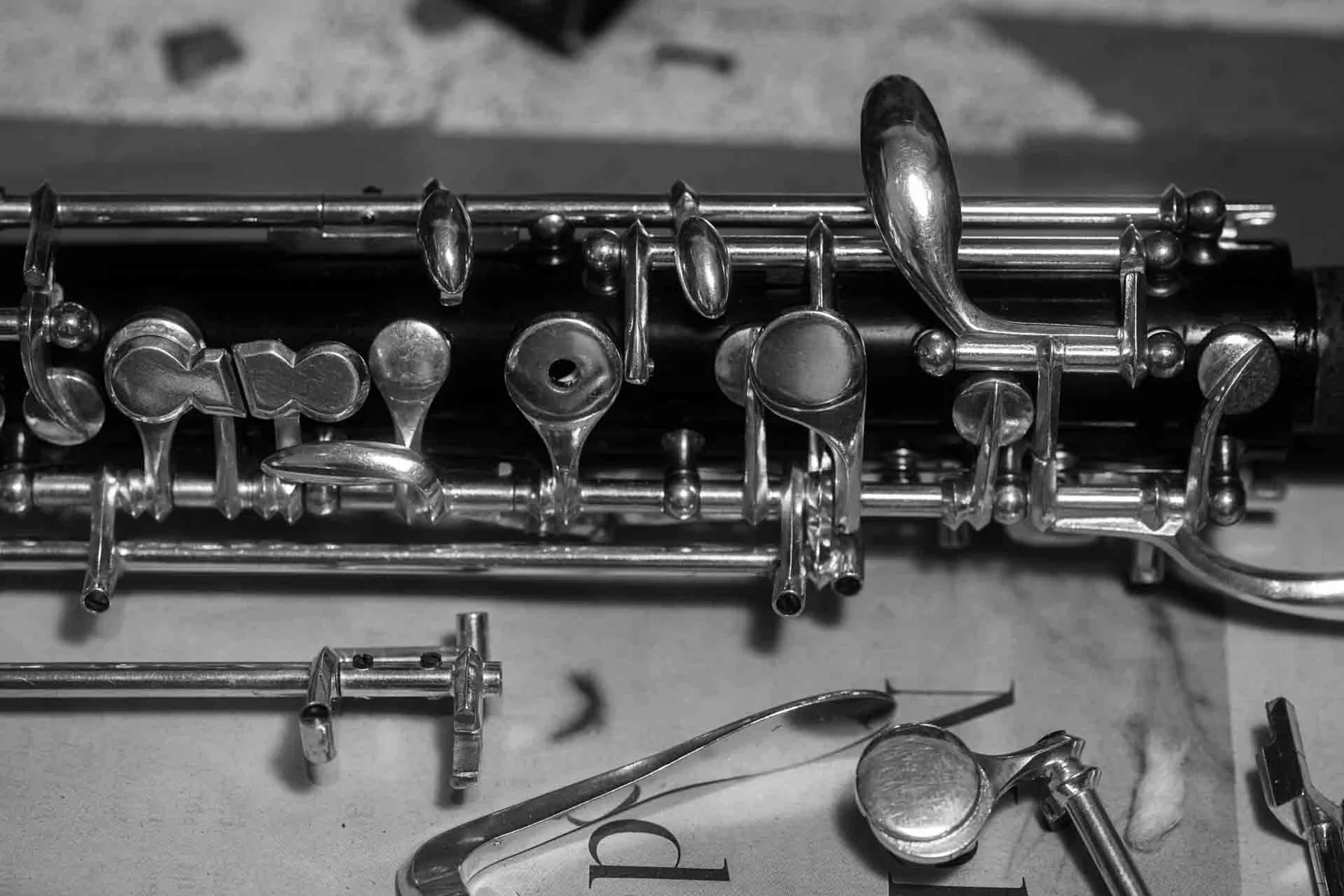 Wide detail of polished silver keywork on an oboe body, resting on the workbench of Florian Köck in Vienna.