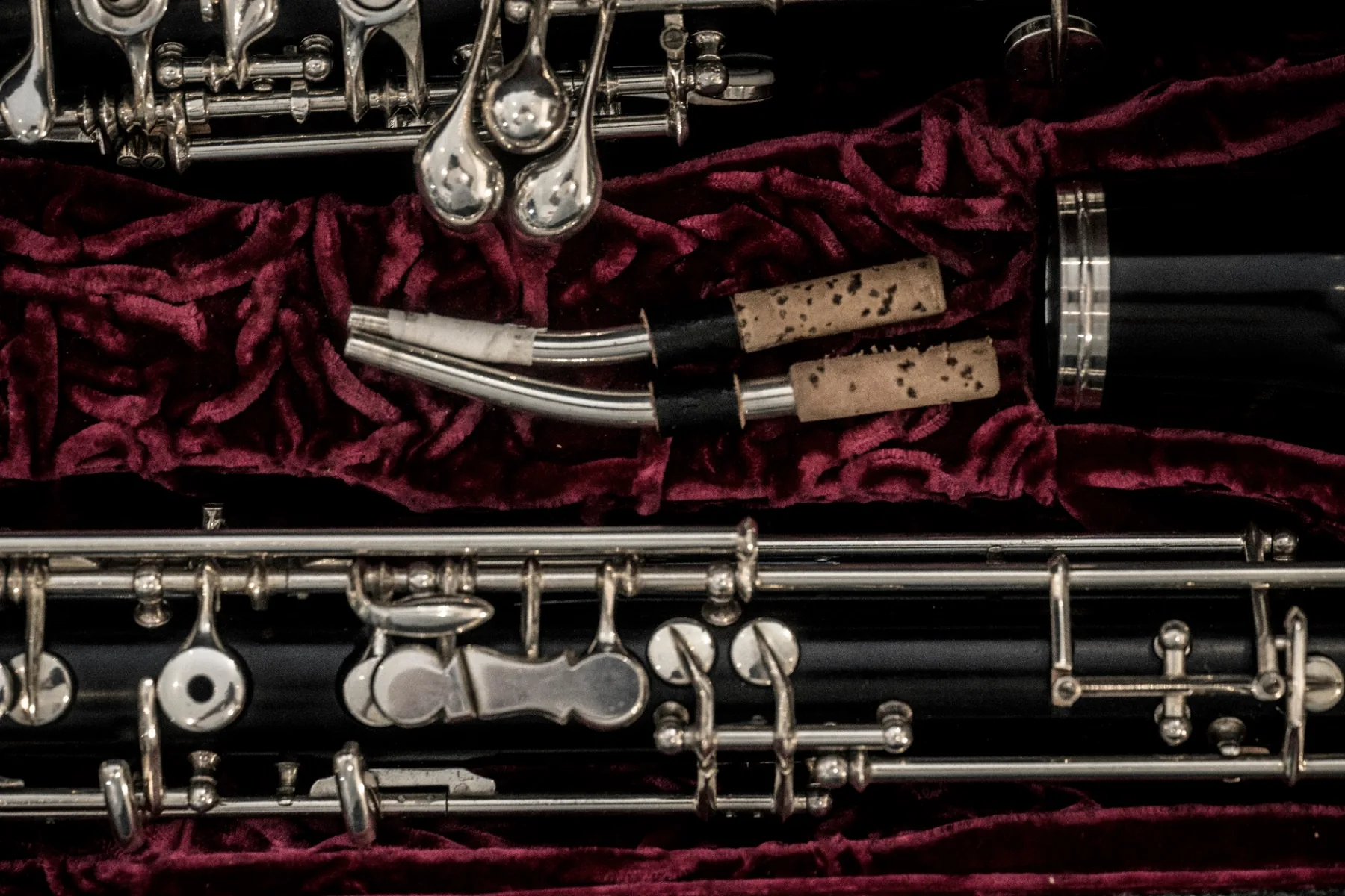 A completed oboe resting on deep red velvet inside its case — the finished instrument at the end of countless small working steps.