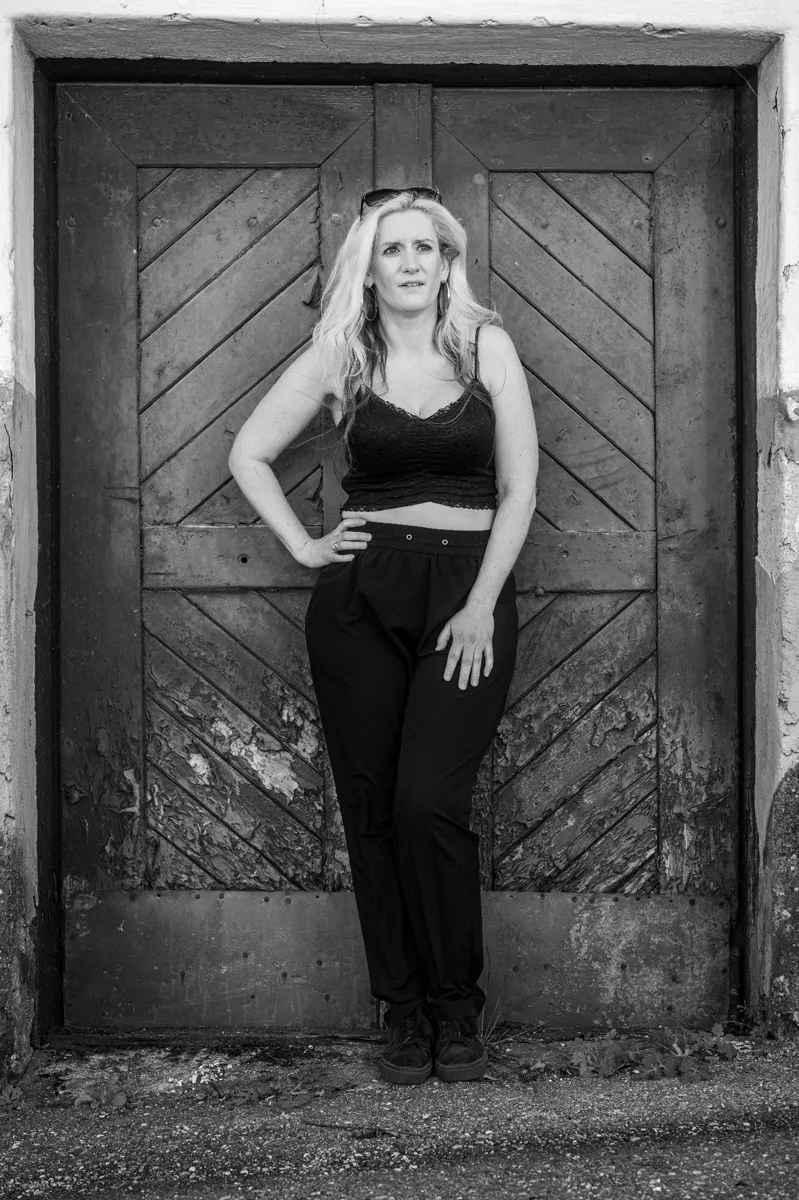 Quiet ending portrait — framed by rustic double door, centered symmetry, contemplative fine art by schopho