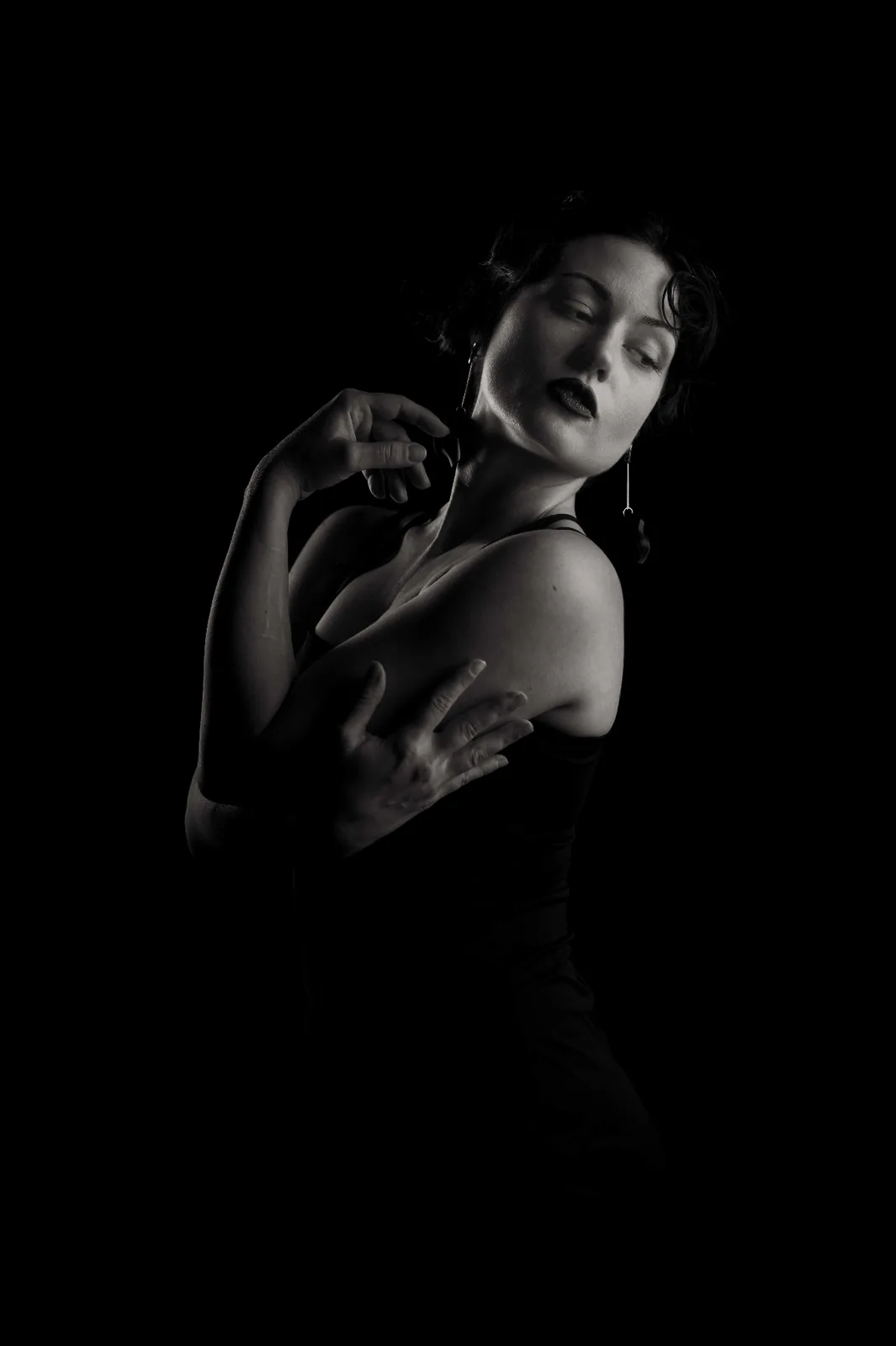 Quiet monochrome studio portrait — woman with eyes lowered, hand resting on shoulder, soft sculptural light from the Monochrome Presence series