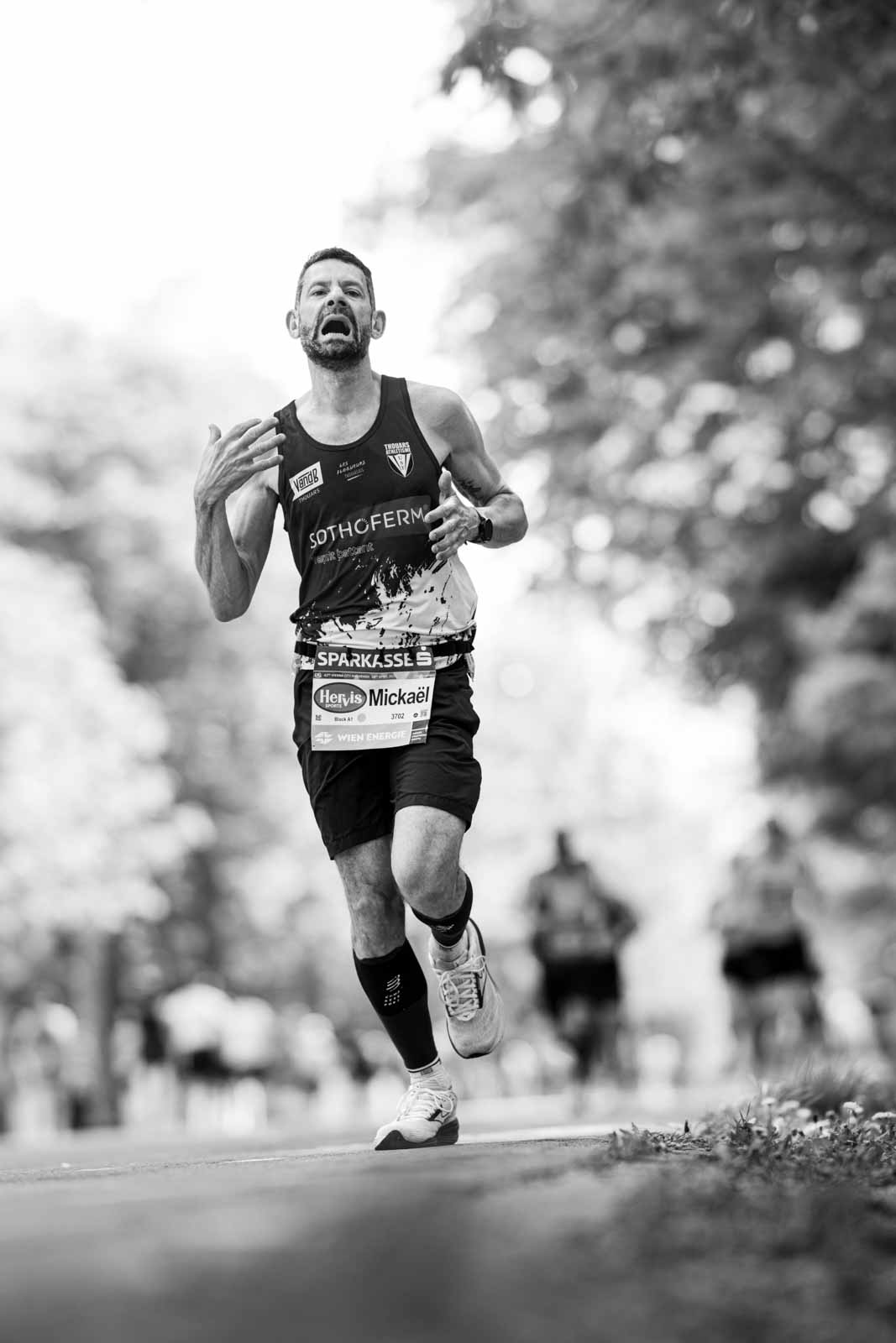 Marathon runner Mickaël in full effort with open mouth at the Vienna City Marathon — black and white editorial photography by Peter Scholz